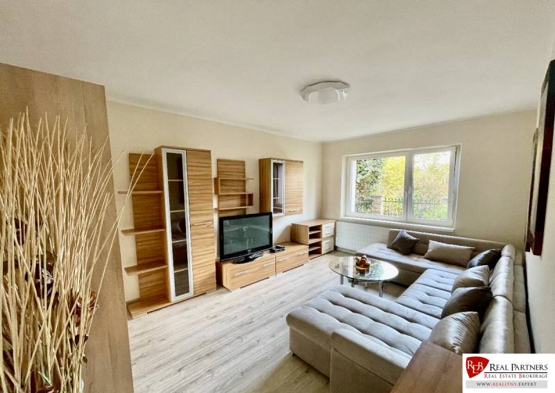 Living room of a two-room apartment with a wooden decor floor and an elegant corner sofa.