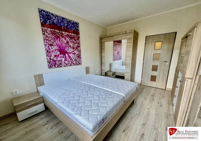 Bedroom in a 2-room apartment with a bed, wardrobe, and wooden decor flooring.