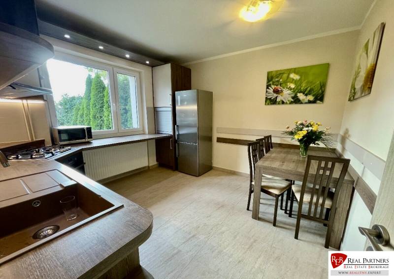 A kitchen in a 2-room apartment with a wooden decor floor and a dining table.