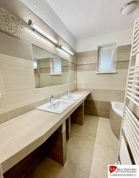 Bathroom in a 2-room apartment with a double sink and tiles in neutral shades.