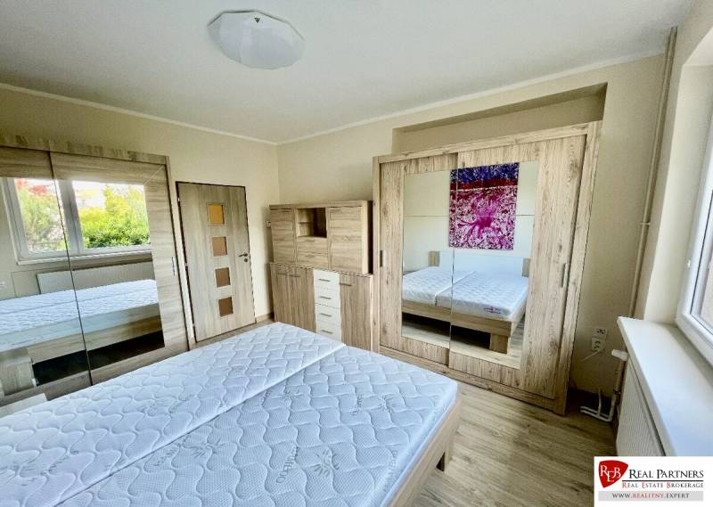 Bright bedroom in a two-room apartment with a spacious wardrobe and a floor with a wooden decor.