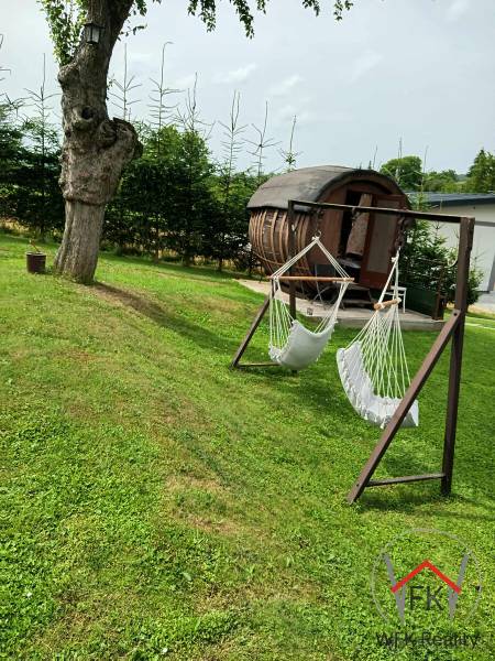 Garden with hammocks and a wooden house in Jasenovce on Jesenovce, suitable for residential plots.