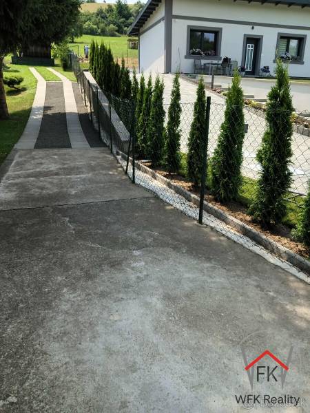 Sidewalk next to the house and thuja trees on the residential property on Jesenovce Street, Jasenovce.