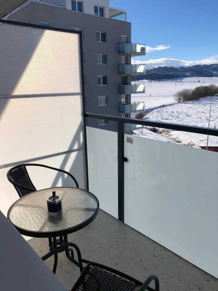 The balcony of a studio apartment on Suchoňova Street in Poprad with a view of the snowy landscape.