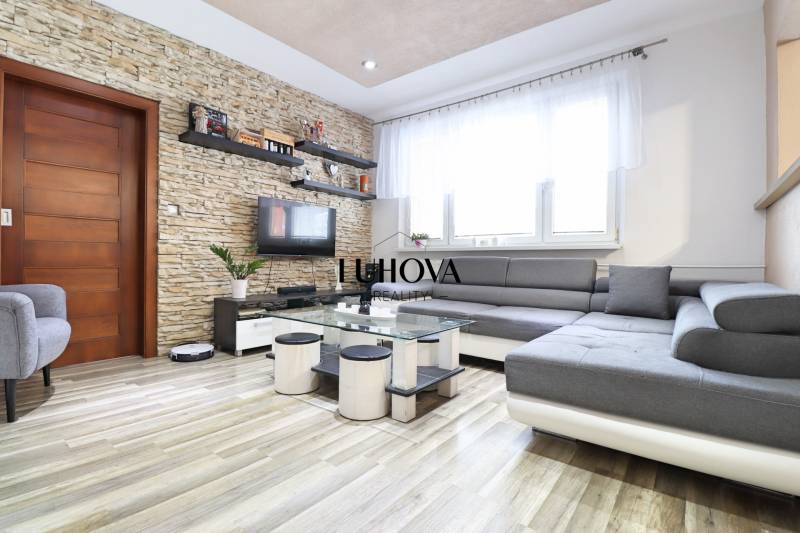 Living room in a 3-room apartment with a wood-decor floor and a stone wall.
