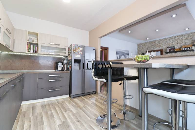 Kitchen in a three-room apartment with a wood-patterned floor and a bar counter.