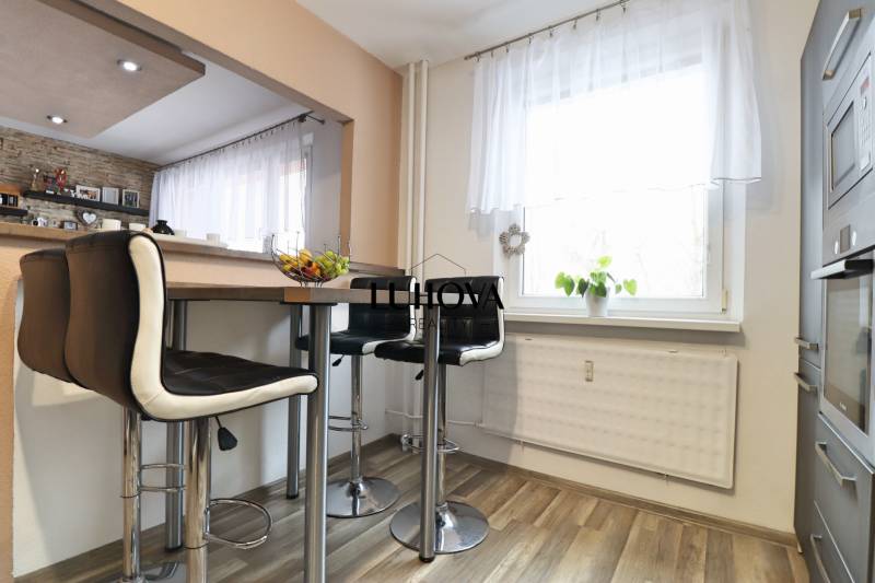 Kitchen corner in a 3-room apartment with a table, chairs, and a window, floor with wooden decor.