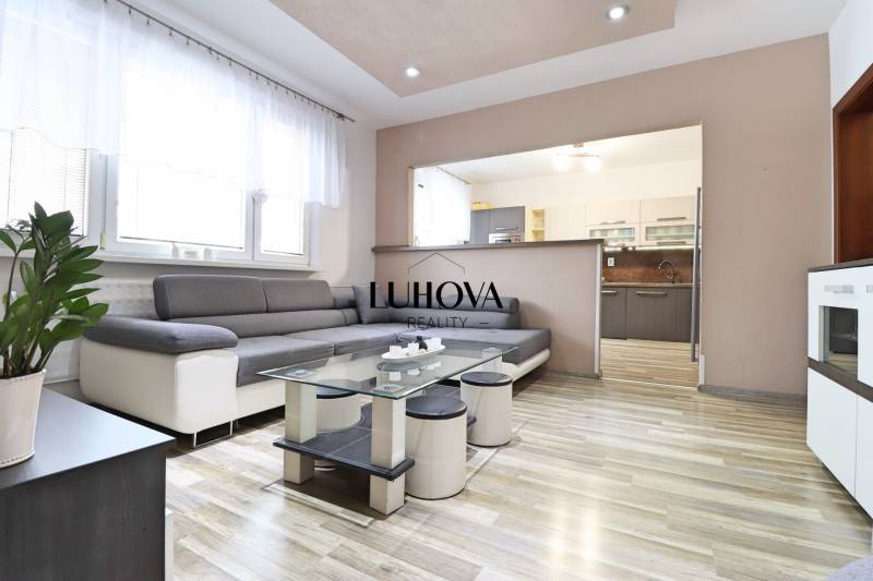 A room with a wooden decor floor, a sofa, and a glass table in a three-room apartment.