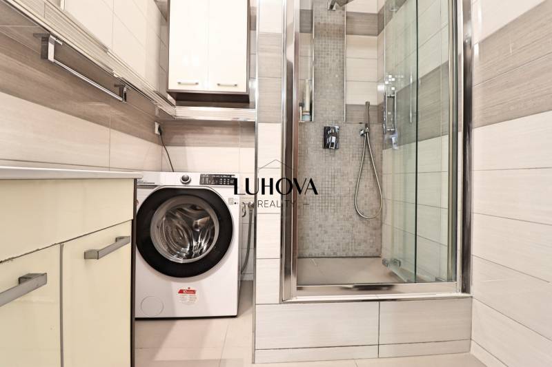 A bathroom in a three-room apartment with a washing machine and a shower.