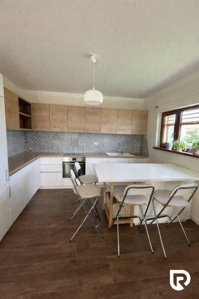 A kitchen in a family house with a wooden decor floor, a dining table, and chairs.