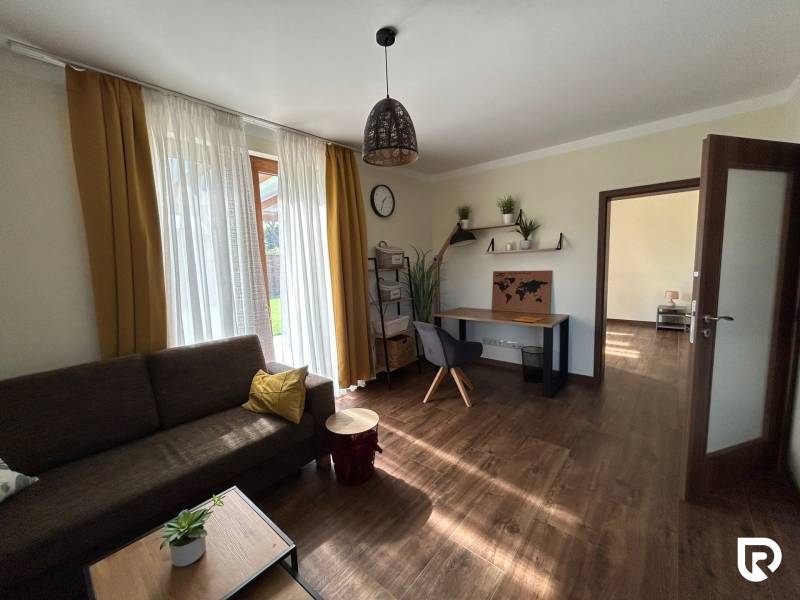 Living room with a sofa, a desk, and a wooden floor decor in a family house.
