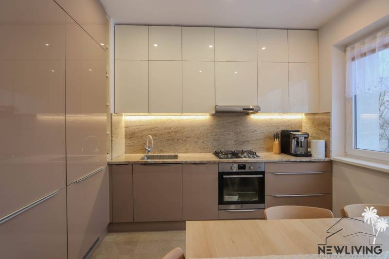 A kitchen in a 3-room apartment with a glossy countertop and stone cladding, floor with a wooden decor.