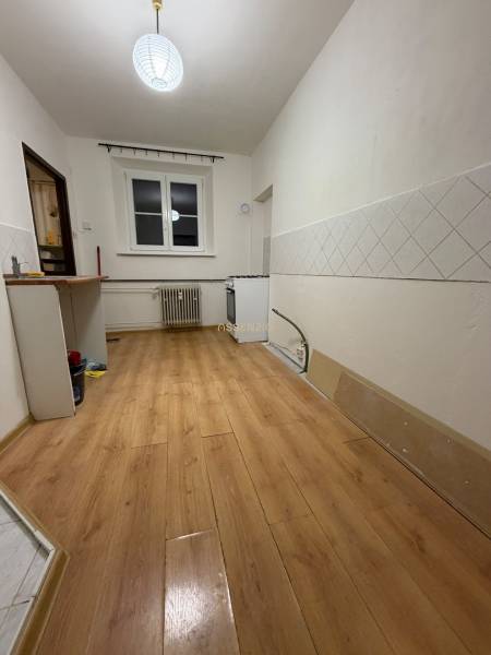 Kitchen in a studio apartment, wooden decor flooring, white tiles on the walls.