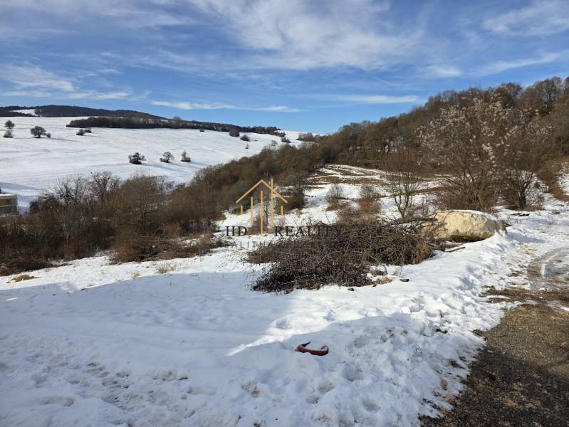 Snow-covered residential lands in Horná Mičiná with a panorama of hills and trees.