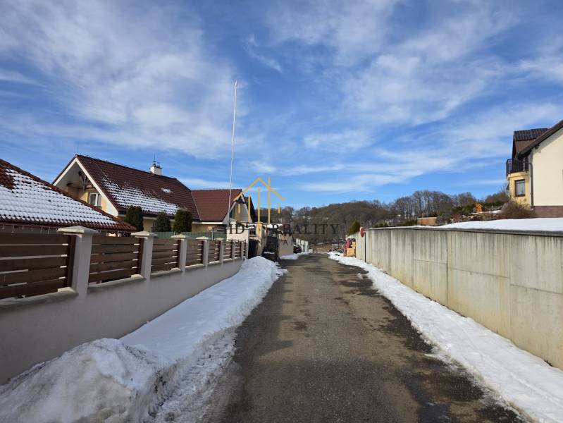 A snowy street with family houses in Horná Mičiná, plots - residential.
