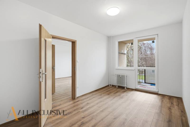 A room in a 3-room apartment with a wooden decor floor and access to a balcony.