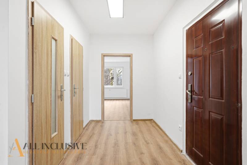 A hallway in a 3-room apartment with a wooden decor floor and wooden doors.