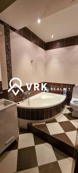 A bathroom in light tones with a corner bathtub in a 3-room apartment.
