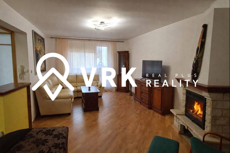 Living room with a fireplace, sofa, and wood-patterned flooring in a three-room apartment.