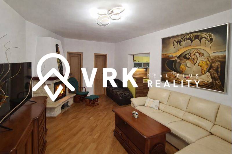 Living room in a 3-room apartment with a fireplace, sofa, and wooden decor flooring.