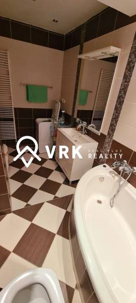 Bathroom in a 3-room apartment with a bathtub, sink, and washing machine, tiled floor.