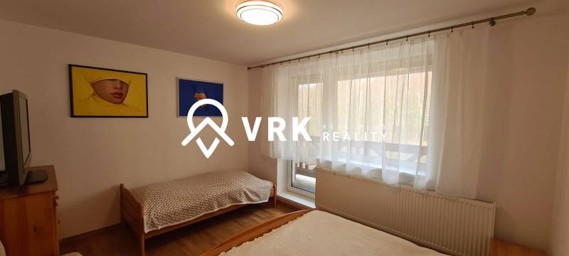 Bedroom in a 3-room apartment with beds, a television, two paintings, and a floor with a wooden decor.