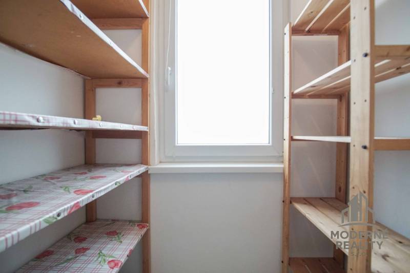 A compact pantry with wooden shelves and a window in a 3-room apartment.