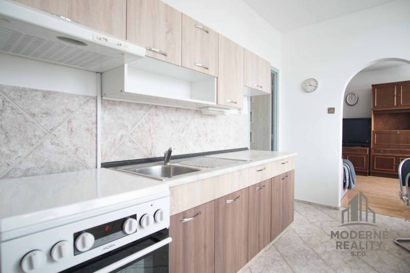 A kitchen in a 3-room apartment with beige cabinets and tiles on the wall.