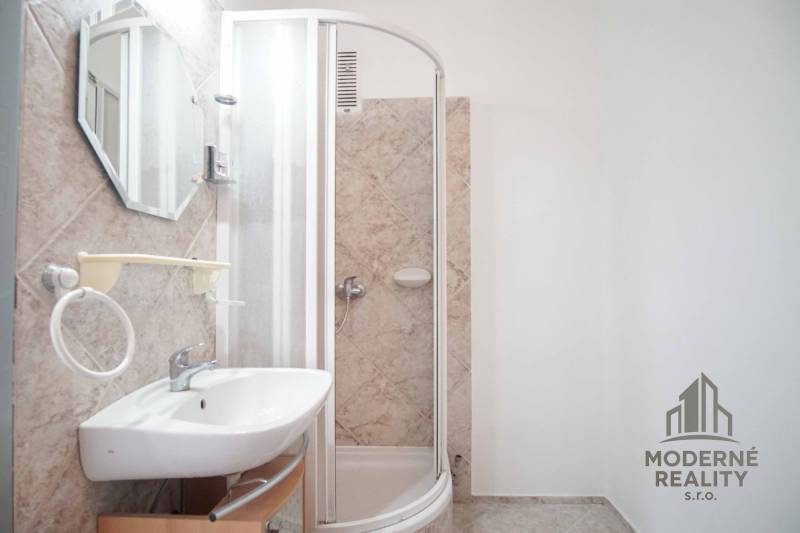 Bathroom with ceramic tiles, shower corner, and sink in a 3-room apartment.