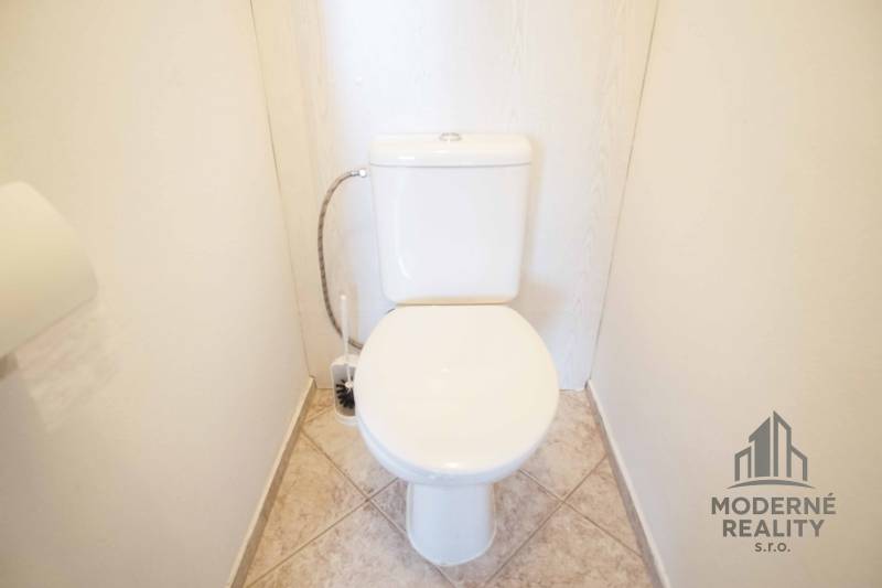 A toilet with a tiled floor in a 3-room apartment.