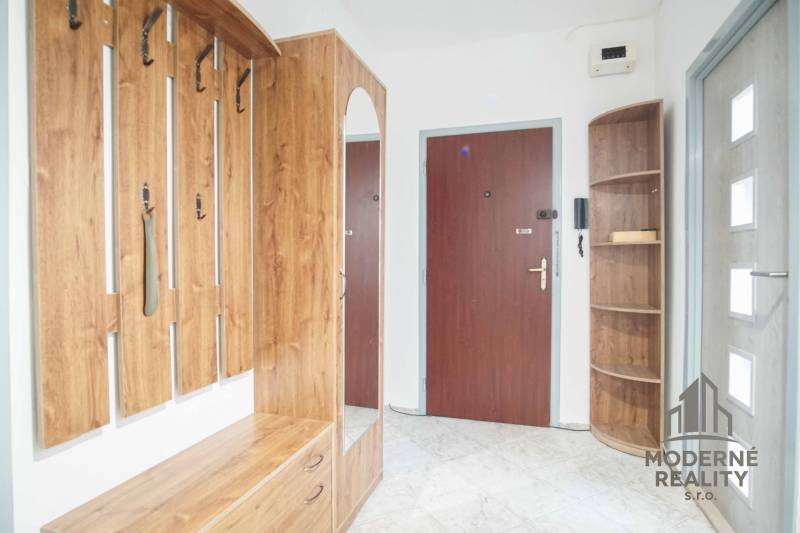 A hallway in a 3-room apartment with a coat rack, cabinets, and a mirror.