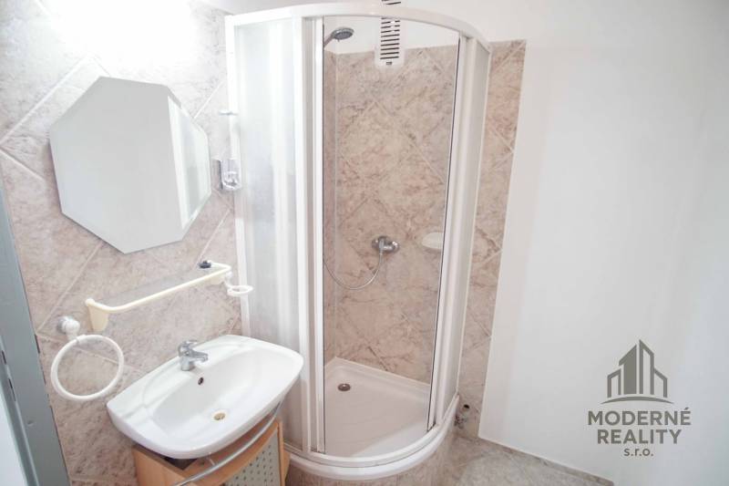 A bathroom in a 3-room apartment with a corner shower and a sink.
