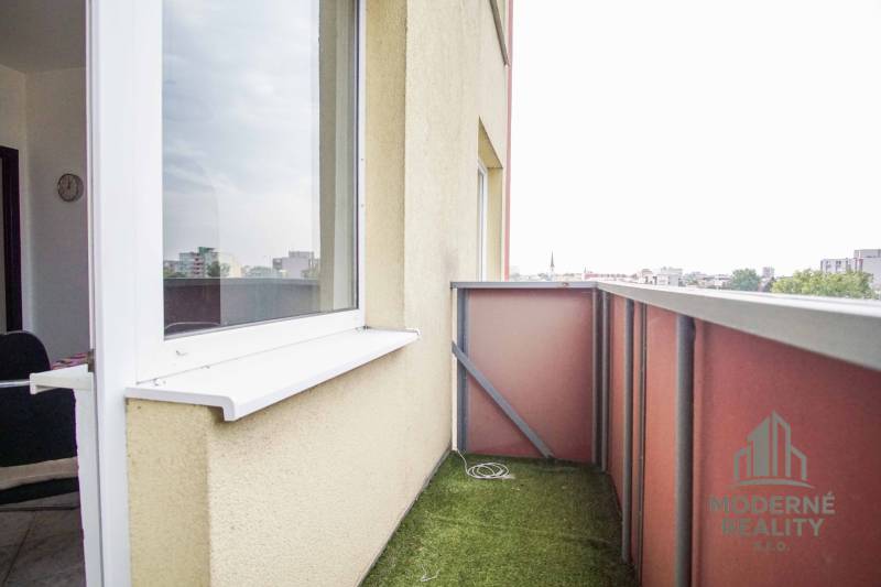 A balcony with artificial grass from a 3-room apartment in Nové Zámky offers a city view.