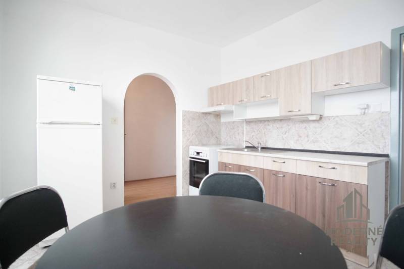 A kitchen in a 3-room apartment with an arched passage and a floor with a wood decor.