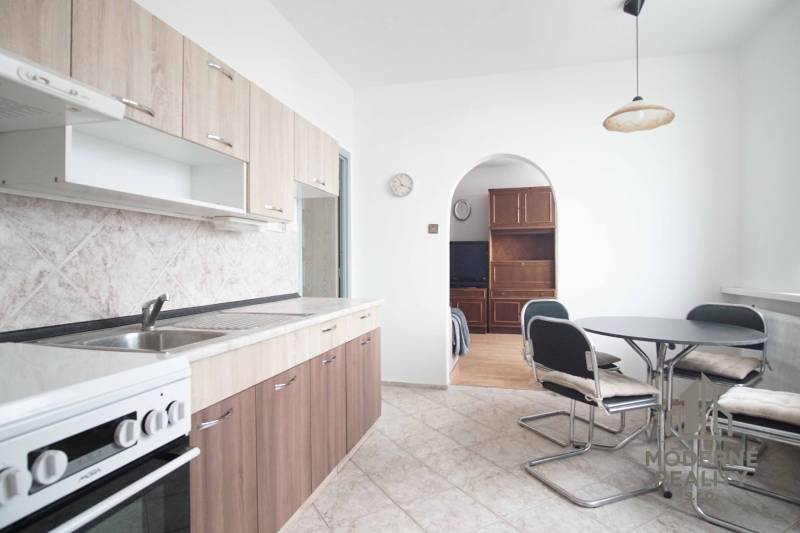 A kitchen with a dining table and cabinets, connected to the living room in a three-room apartment.