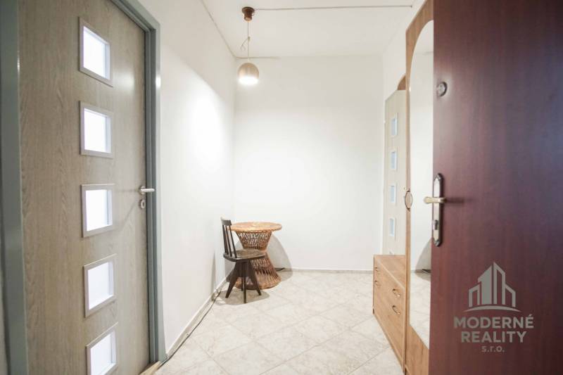 A bright hallway with ceramic tiles, a wooden table, and a chair in a 3-room apartment.