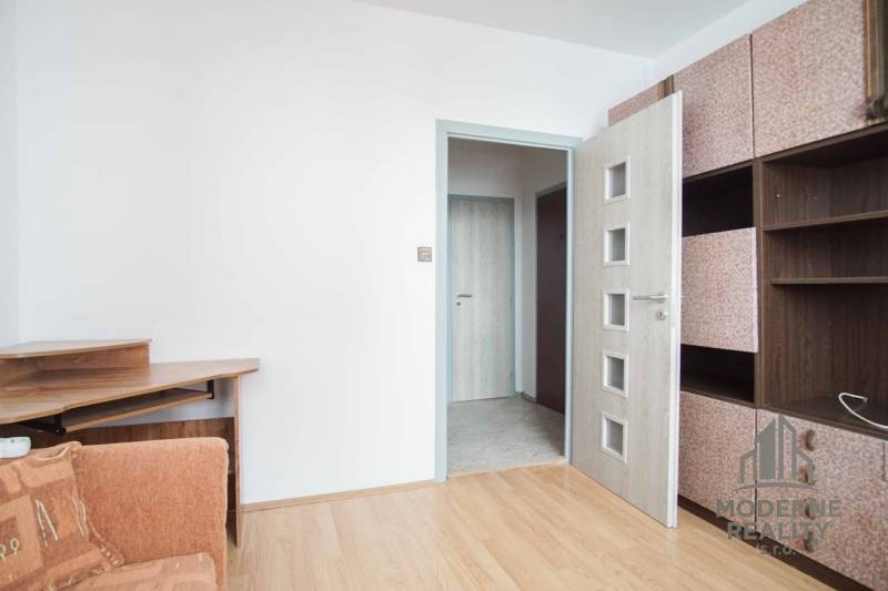 Interior with a sofa, wooden decor flooring, and a built-in wardrobe in a 3-room apartment.