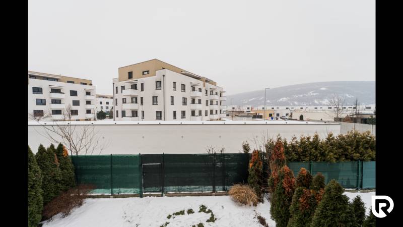 View from a 2-room apartment onto the snowy Hroznová street in Trenčín with apartment buildings.