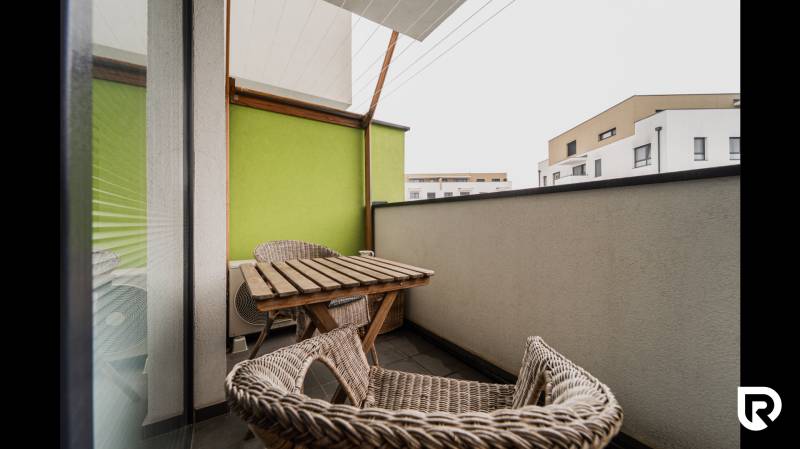 A balcony with rattan furniture and a green wall in a 2-room apartment, Trenčín, Hroznová.