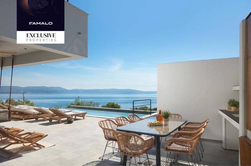 The terrace of the villa in Labin with a view of the sea, sunbeds, and a dining table.