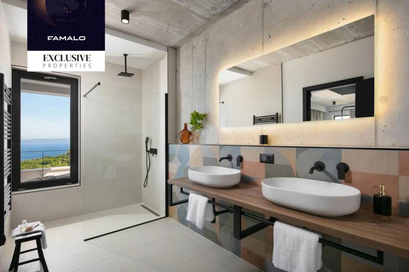 A bathroom in a villa with sinks, a large mirror, and a view of the sea.