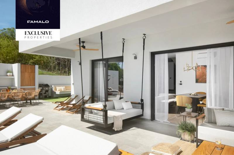 Exterior of the villa with a terrace in Labin. Relaxation loungers, hanging chair, dining area.