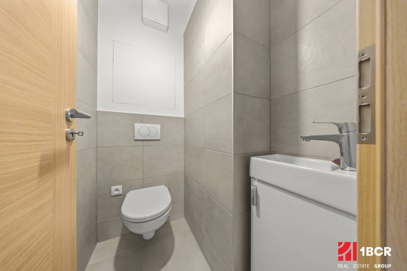 A bathroom in a three-room apartment with white sanitary ware and light tiles.