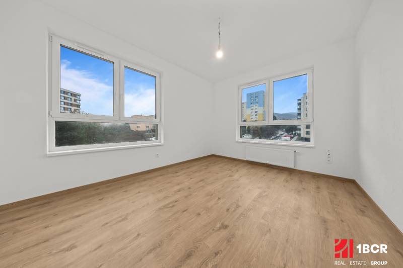A room in a 3-room apartment with a large window and a floor with a wooden decor.