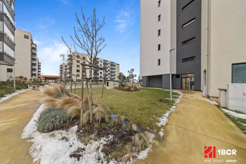 The exterior of an apartment building in Bratislava-Rača on Rudroffova, with modern architecture and landscaped surroundings.