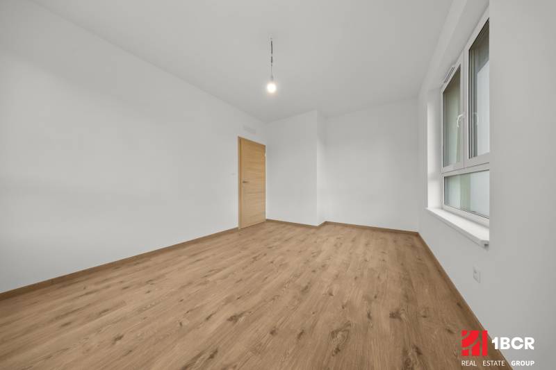 A room in a 3-room apartment with a wooden decor floor and white walls.
