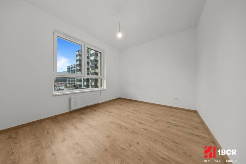 A room in a 3-room apartment with a window and a floor with a wood decor.