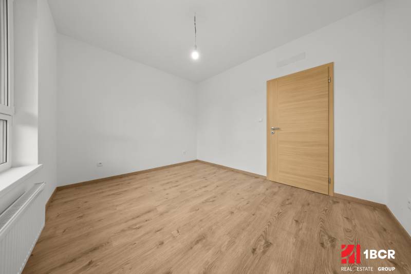 A room in a 3-room apartment with white walls and a wooden decor floor.