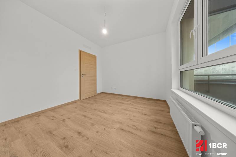 A spacious room with a wooden decor floor in a 3-room apartment.