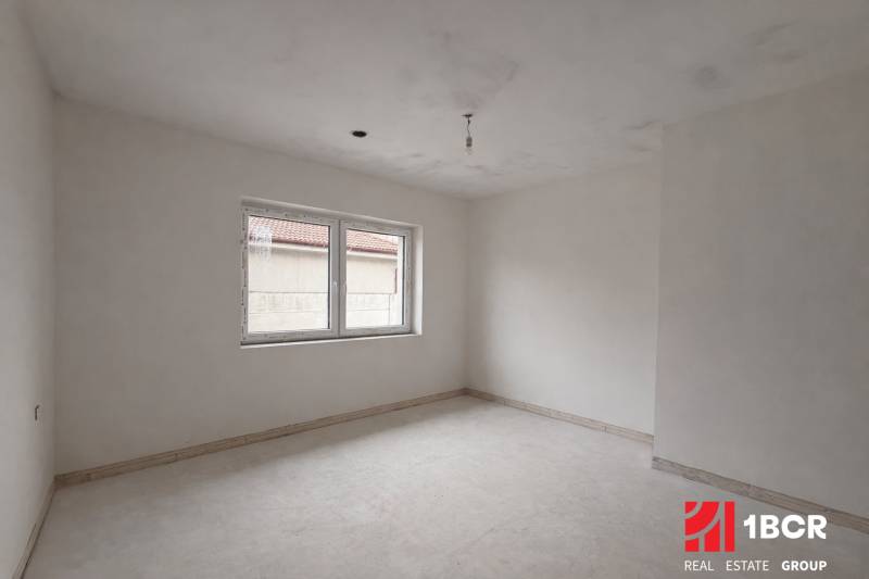 An empty room with a large window in a family house, white walls, floor with wooden decor.